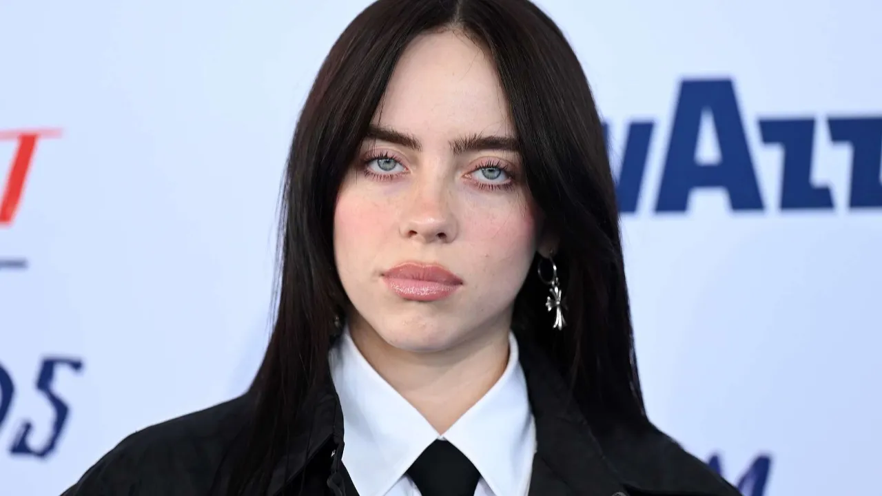billie eilish with black tie and black vest looking straigh to the camera with her beautifull eyes